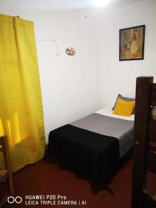 1 dormitorio con 1 cama con cortina amarilla en Bruna Departamentos en San Fernando del Valle de Catamarca