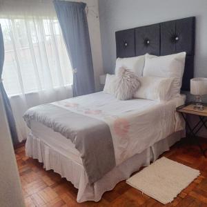 um quarto com uma cama grande e uma janela grande em MaThwala guesthouse em Vanderbijlpark