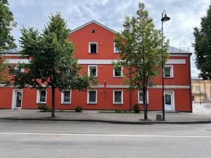 a red building with two trees in front of it at Bell Tower Apartment in Plungė
