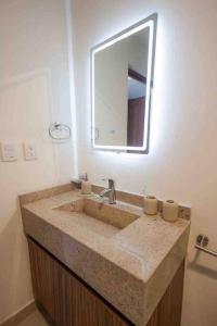 a bathroom with a sink and a mirror at Departamento Puerta Al Mar in Conchal
