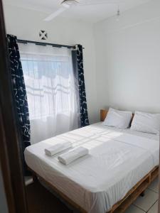 una camera da letto con un letto con due asciugamani bianchi di Gianna’s Stays a Mombasa