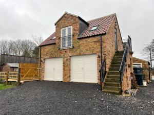 a brick house with two garage doors and a staircase at Roseberry View Barn, Northallerton in Northallerton