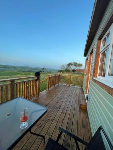 a deck with a table and wine glasses on it at Keepers Shepherd hut with Hot Tub in Whitby