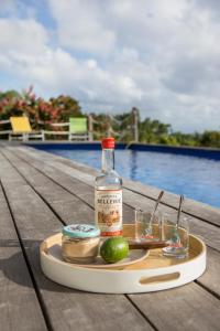 une bouteille d'alcool sur un plateau sur une table près d'une piscine dans l'établissement Villas Coccoloba & Jacaranda, à Capesterre