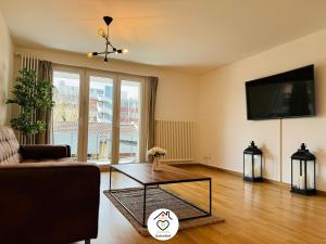 uma sala de estar com um sofá e uma mesa de café em vidro em Family M Apartments 7 em Sempach