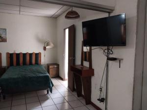 a bedroom with a bed and a flat screen tv at Hotel Luigi in San Salvador