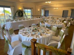 uma sala cheia de mesas e cadeiras com toalhas de mesa brancas em Kingarth Hotel em Kilchattan