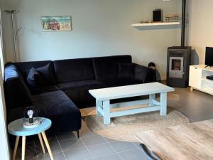 een woonkamer met een zwarte bank en een tafel bij Beachhouse Wenduine 25 in Wenduine