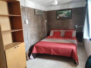 Habitación pequeña con cama con almohadas rojas en Bruna Departamentos en San Fernando del Valle de Catamarca