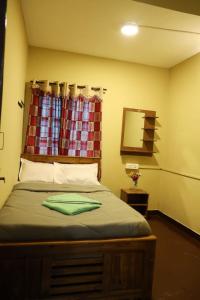 a bedroom with a bed with a window and a mirror at LA SIESTA in Ooty