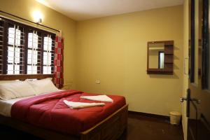 a bedroom with a bed with red sheets and a mirror at LA SIESTA in Ooty