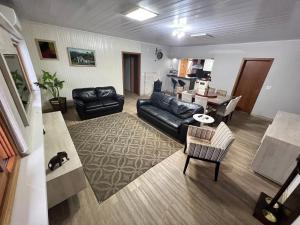 ein Wohnzimmer mit einem schwarzen Ledersofa und einem Tisch in der Unterkunft Casa mais Central de Gramado in Gramado