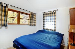 a bedroom with a blue bed and a window at Chalets Alpins 13 Chemin Alpin in Stoneham