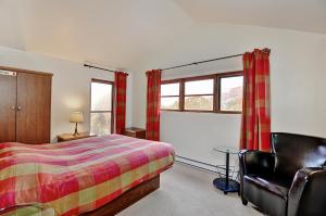 a bedroom with a bed and a chair and windows at Chalets Alpins 13 Chemin Alpin in Stoneham