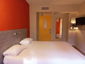 a bedroom with a large white bed with a yellow door at ibis budget Saint-Brieuc Yffiniac in Yffiniac