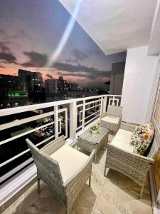 a balcony with chairs and tables and a view of a city at Super Cozy n´Confortable apart. in Ensanche Los Minas