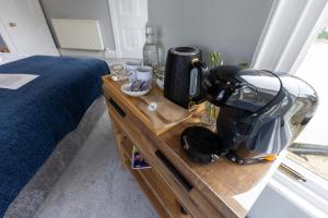 una cafetera en una mesa de madera junto a una cama en The Crossing Bed and Breakfast, en Kingussie