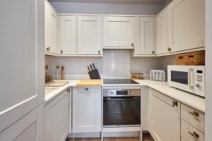 a white kitchen with white cabinets and appliances at Host & Stay - Poplar Villas in Ramsgate