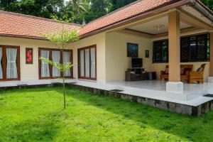 a house with a green lawn in front of it at Calm Haven Villa with Amabela Garden Lovina Beach in Lovina