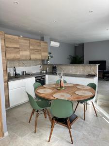 eine Küche mit einem Holztisch und grünen Stühlen in der Unterkunft Villa Romaine in Vaison-la-Romaine