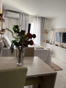 a vase of flowers on a table in a living room at Flat JK 103 in Juazeiro do Norte