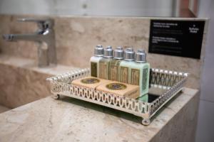 un estante de metal con 4 botellas en la barra del baño en Sofistic Hotel, en Itapema