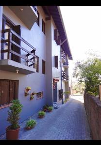 a white building with a balcony and potted plants at Pousada Folhas de Outono in Canela