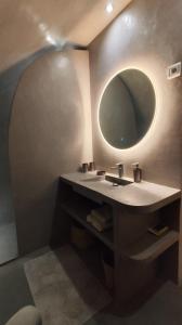 uma casa de banho com um lavatório e um espelho redondo em Le logis du Barry em Montpeyroux
