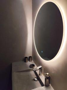 a bathroom with a sink with a round mirror at Le logis du Barry in Montpeyroux