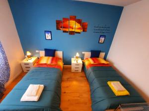 two twin beds in a room with blue walls at New Bedrooms Mamma Gigetta in Noventa di Piave
