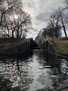 a small dam on a river with trees in the background at Stationshus apartment in Hallstahammar