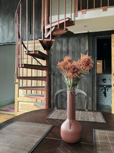 a vase with flowers on a table with a staircase at Stationshus apartment in Hallstahammar