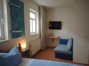 a living room with a blue chair and a tv at Bed and Breakfast Wehlen in Stadt Wehlen