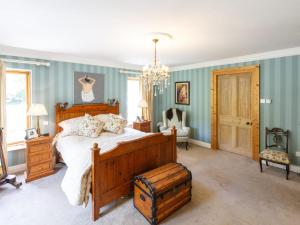 um quarto com uma cama grande e um lustre em Cherrygarth Cottage em White Hall