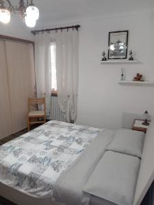 ein weißes Schlafzimmer mit einem Bett und einem Stuhl in der Unterkunft La tana di Pisolo in Vicoforte