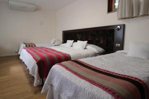 two beds in a hotel room withskirts at Atankalama in Calama
