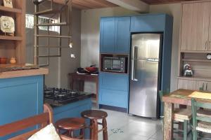 La cuisine est équipée de placards bleus et d'un réfrigérateur en acier inoxydable. dans l'établissement WolfsHaus: Sossego junto a natureza a 30km de Ctba, à Campina Grande do Sul