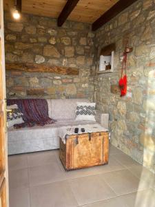 a stone room with a couch and a trunk at Bujtina Salko in Muçaj