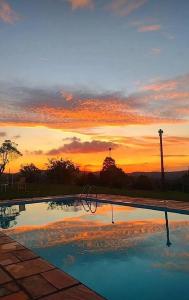 a swimming pool with a sunset in the background at Chácara Áquila in São Roque