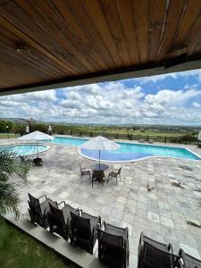 a pool with chairs and a table and an umbrella at Flat Villa Monte Castelo in Bezerros