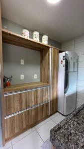 a kitchen with a stainless steel refrigerator and wooden cabinets at Flat Villa Monte Castelo in Bezerros