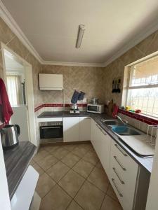 a small kitchen with white cabinets and a sink at Holiday Flat at Vaaldam Sgt Pepper's in Oranjeville