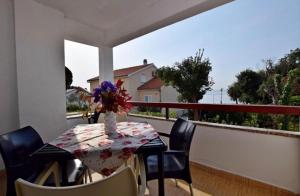 a table with a vase of flowers on a balcony at Apartment Marina in Petrcane
