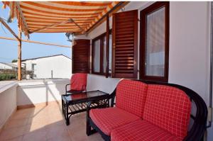 eine Veranda mit zwei roten Stühlen und einem Tisch in der Unterkunft Apartment Marina in Petrcane