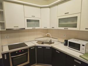 cocina con armarios blancos, fregadero y microondas en Judita Apartments & Rooms, en Međugorje