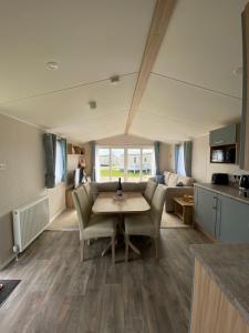a kitchen and living room with a table and chairs at VerbZen Holidays Caravan at St Osyth Beach, Clacton-on-Sea in Saint Osyth