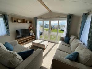 a living room with two couches and a tv at VerbZen Holidays Caravan at St Osyth Beach, Clacton-on-Sea in Saint Osyth