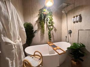 Zaya luxury apartment في الرياض: حمام مع حوض ونباتات على الحائط