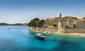 un bateau dans l'eau en face d'un château dans l'établissement APARTMENTS Ana by the SEA, à Lumbarda