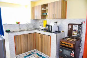 a small kitchen with a stove and a microwave at Raven Suites in Kakamega